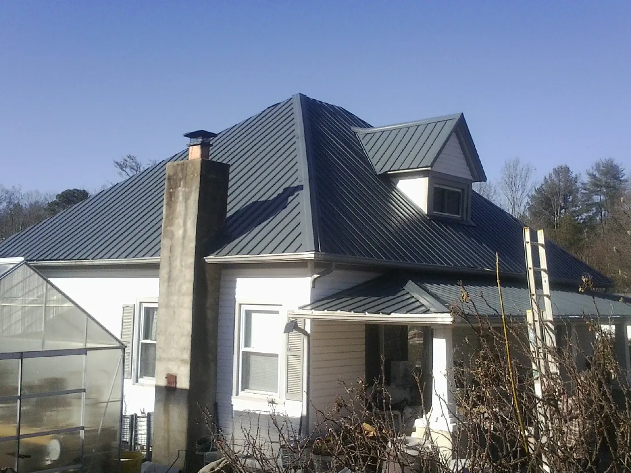 Dark blue standing seam metal roof on a white farmhouse with dormer — Slate & Tile Roof Repair by Roofing Brothers in Bernardston