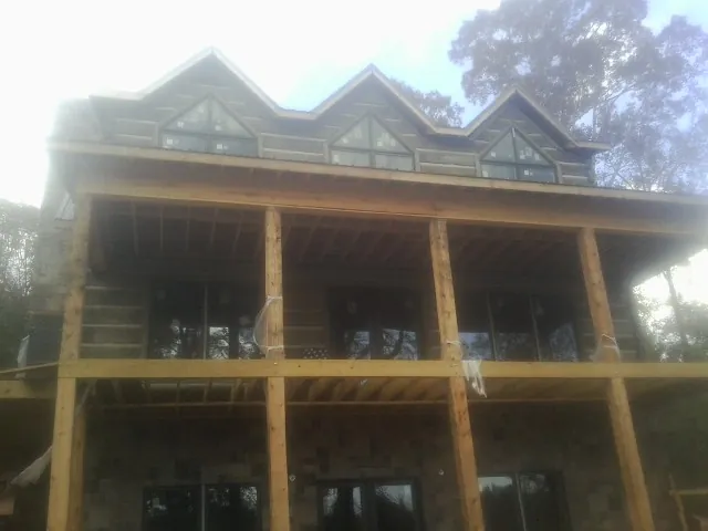 Dormers and porch framing on a large log home under construction — Roof Coating work by our crew in Bernardston