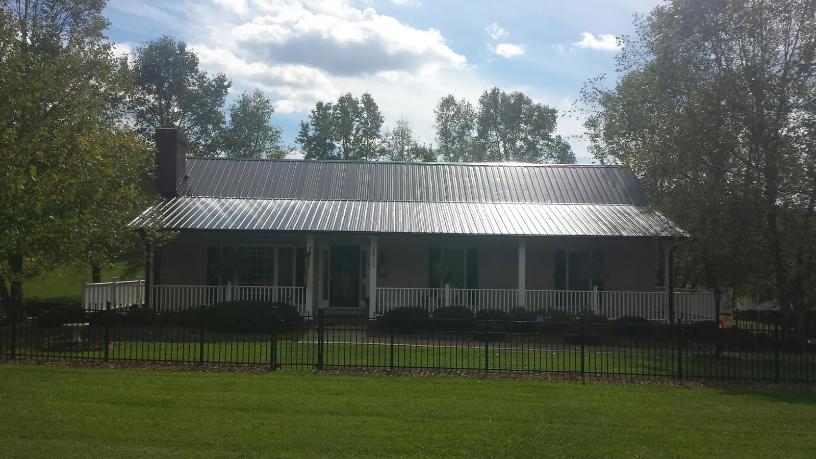 Gray metal roof on a brick ranch with a full width front porch — Gutter Guard Installation work by our crew in Bernardston