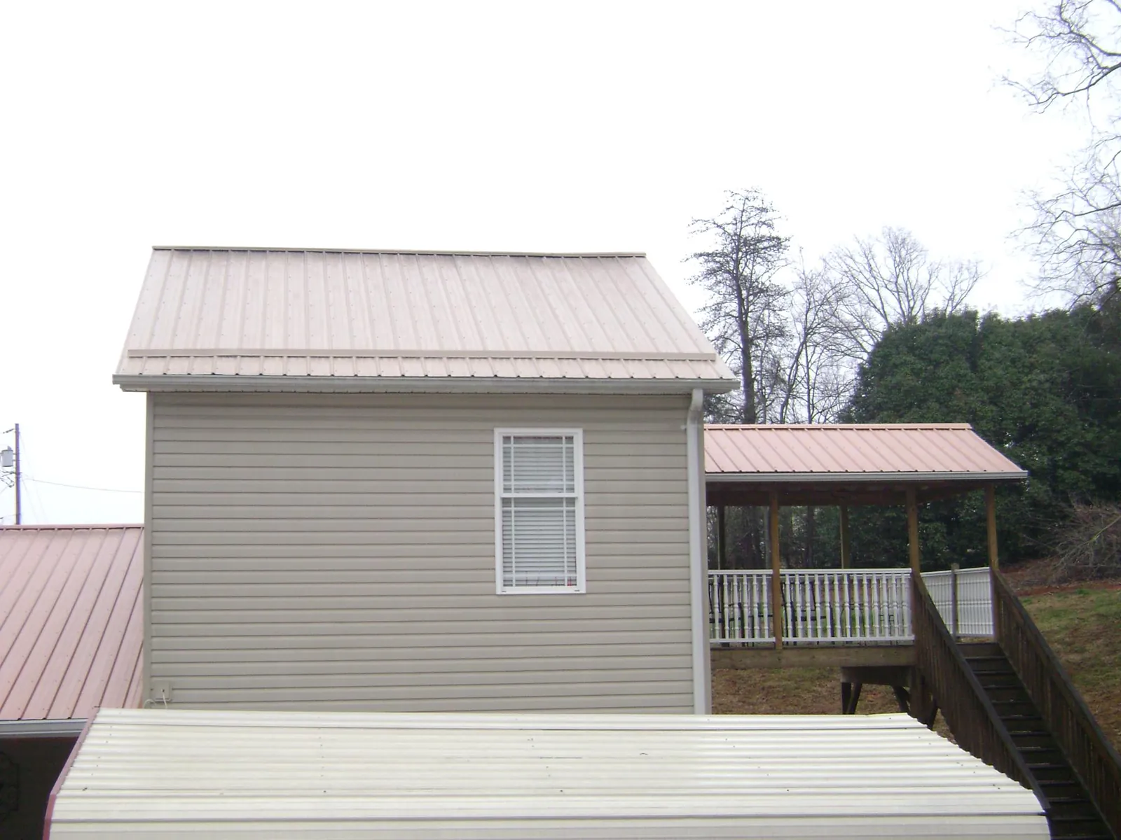 Tan metal roofs on a two story addition and attached porch, from a Roof Replacement job in Bernardston