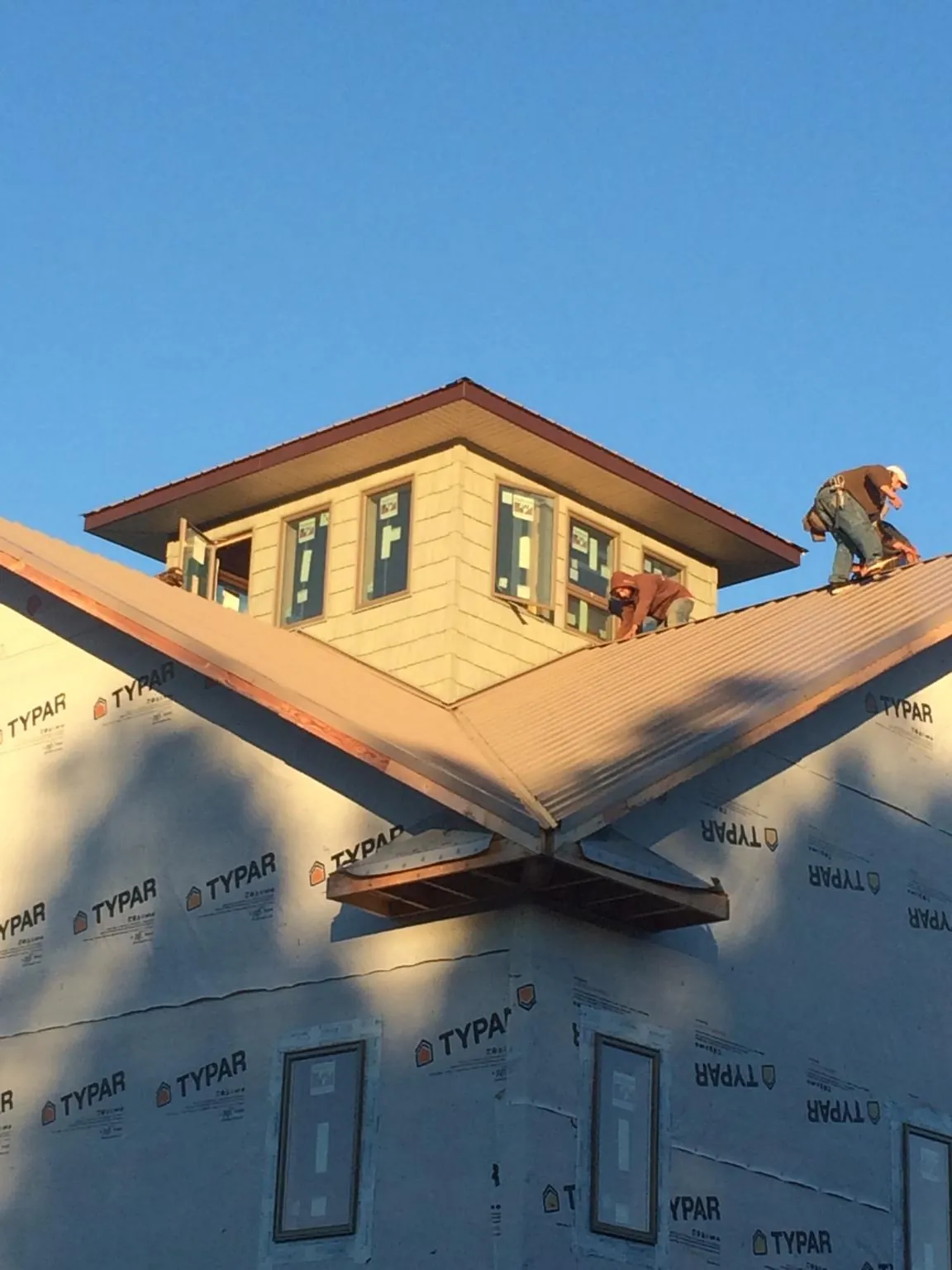 Roofers working around a rooftop cupola on a new metal roof at sunset — Roof Waterproofing in Bernardston by Roofing Brothers